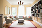 Mix of styles in old, traditional building - light-grey upholstered furniture on modern rug with decorative light fitting and carved shelf supports