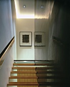Open wooden stairs between wall with flush handrail in recess and shiny, black supporting wall