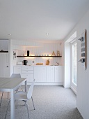 White wooden kitchen in rustic Scandinavian style with 50s chairs and skateboard on wall