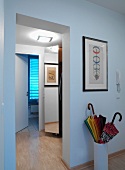 Illuminated hallway in contemporary apartment with framed pictured and umbrella stand