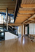 Swing in open-plan living space under gallery, stainless steel stove pipe and steel structure in modern wooden house