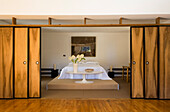 Bedroom with wooden sliding doors and round table in front of the bed