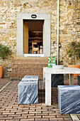 Outdoor seating area with marble table and stools in front of stone wall