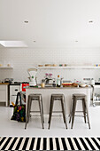 Kitchen with metro tiles, bar stools and striped carpet