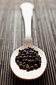 Black peppercorns on spoon