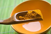 Turmeric powder on a wooden scoop