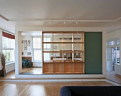 Spacious, modern kitchen-dining room with wooden partition with integrated shelving and serving hatch