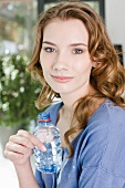 A young woman holding a small bottle of water