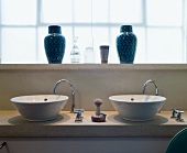 Two sinks & two blue vases on windowsill