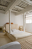 Bedroom with rustic wooden beamed ceiling in white and cream-coloured bed