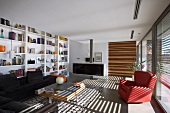 Patterns of light and shade in spacious, bright living room with extensive bookcase and striped sliding door