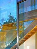 View of wooden staircase through glass wall