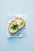 A slice of baguette topped with butter and chives