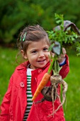 Little girl holding assorted root vegetables in her hand
