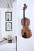 Violin as wall decoration in a room decorated in white with pictures