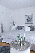 Bedroom in white with decorative pillows and silver-colored decorative elements