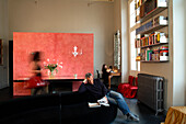 Wohnzimmer mit roter Wandgestaltung, Bücherregal und Vintage-Heizkörper