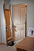 Hand-made, full-length mirror constructed from vintage skis and ski boots next to open door
