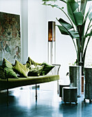 Green sofa with green cushions, houseplant and art objects