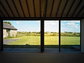 Leerer Wohnraum mit raumhohen Terrassenfenstern und Ausblick