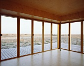 Leerer holzverkleideter Raum mit Terrassentüren und Landschaftsblick