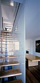 Staircase with wooden treads in front of glass partition in modern living space