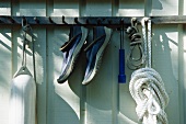 Eine Boje, ein Paar Schuh und Seil hängen an Haken am Hauswand