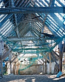 Gespanntes Netz unter Dachstuhl in baufälliger Scheune