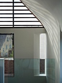 Glass balustrade in front of ceiling-height windows with half-closed blinds