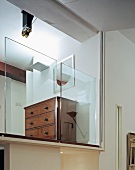 Antike Kommode hinter halbhohen Glaspanelen auf Galerie