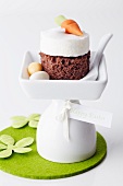 A sponge cake topped with meringue and a marzipan carrot and served with sugar Easter eggs
