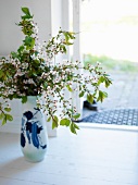 Vase of blossoming twigs on floor
