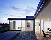 Roof terrace at dusk with view into living room and office