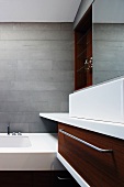 Detail of grey tiled, designer bathroom with nut wood cupboard doors on washstand