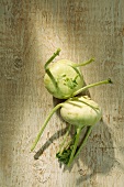 Two kohlrabis on a wooden surface