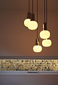 Lit retro light fittings above slit window with view of brick wall