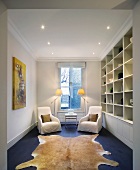 Fitted shelving and seating area in front of window in narrow room