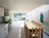 Modern kitchen-dining room with long table beneath skylight