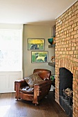 Antique leather armchair next to historic, exposed brick chimney breast