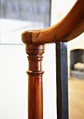 Antique, turned, varnished wooden newel post next to metal baluster