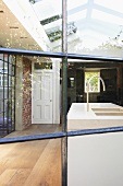 View of purist, designer kitchen with sink in kitchen island through historic, metal lattice window