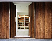 An open door in a wooden wall with a view onto a book shelf