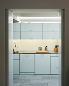 Simple, white fitted kitchen with grey tiled floor