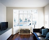 Living room with mixture of styles - modern leather sofa combined with seating on trunk in bay window