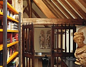 Modern bookcase and antique bust in old, converted barn with historic, wooden-slatted doors