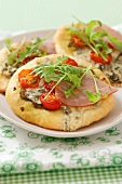 Mini pizzas with ham, blue cheese, rocket and cherry tomatoes