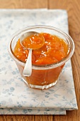 A jar of apricot jam with a spoon