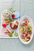 Sandwich board with radish salad, cold cuts and rolls and potato salad with zucchini and roast beef