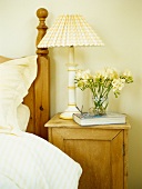 Bedside table with lamp, book and flowers