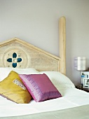 Yellow and violet scatter cushions on romantic wooden bed